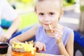 Little girl eating rench fries with sauce at street cafe outside. Royalty Free Stock Photo