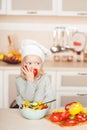 Little girl eating tomato while cooking salad in Royalty Free Stock Photo