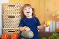 Little girl eating tomato in the kitchen Royalty Free Stock Photo