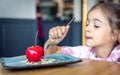 A little girl eats a cherry-shaped chocolate mousse, an unusual cherry cake Royalty Free Stock Photo