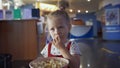 Little girl eats popcorn in movie theater. Media. Cute girl eating popcorn in waiting room at cinema. Pretty girl cute