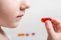 A little girl eats a vitamin in the form of a bear. The concept of strengthening children& x27;s health with multivitamin