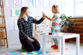 Little girl and educator holding hands, talking and playing in playroom. Interesting logic and intelligence game for