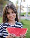 Little girl in an elegant dress and hat eats a watermelon