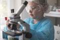 Little girl at an elementary school, using microscope research, testing in science class. Toddler girl doing Royalty Free Stock Photo