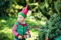 Little girl in elf sweater and hat waiting for a Christmas in the wood. Half-length portrait of a little child near the christmas Royalty Free Stock Photo