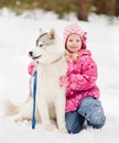 Little girl embracing hasky dog in winter park