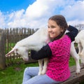 Little girl embracing a kid goat on a farm.