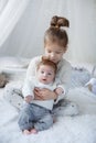 Cute girl with a newborn baby brother relaxing together on a white bed Royalty Free Stock Photo