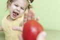 A little girl emotionally refuses the proposed tomato. children do not like vegetables Royalty Free Stock Photo
