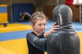 The little girl is engaged in martial arts with a training manikin. The child trains in the wrestling hall. The child is Royalty Free Stock Photo