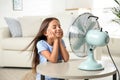 Little girl enjoying air flow from fan. Summer heat