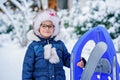Little girl enjoying a day out playing in the winter forest. Portrait of cute preschool child with glasses with sled Royalty Free Stock Photo
