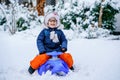 Little girl enjoying a day out playing in the winter forest. Portrait of cute preschool child with glasses with sled Royalty Free Stock Photo