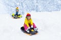 Little girl enjoying a sleigh ride. Child sledding. Toddler kid riding a sledge. Children play outdoors in snow. Kids sled in the