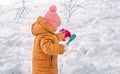 A Little Girl enjoys playing In The Snow. A three-year-old girl in warm clothes plays outdoors in the winter season. Family winte