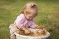 A little girl enthusiastically plays with mud in a basin