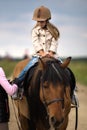Little girl in equestrian helmet riding a horse