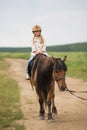 Little girl in an equestrian helmet riding a horse. Girl on a horse walk in nature Royalty Free Stock Photo