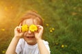 A little girl of European appearance with light hair puts yellow dandelion flowers to her eyes and enjoys the summer, Royalty Free Stock Photo