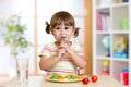 Little girl examines Brussels sprouts. Child with healthy food sitting at table in nursery Royalty Free Stock Photo