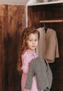 Little girl examines clothes in a closet