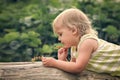 Little girl examines currant berries in the garden