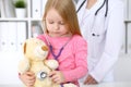 Little girl examining her Teddy bear by stethoscope. Health care, child-patient trust concept. Royalty Free Stock Photo