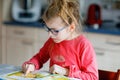 Little girl with eyeglasses learning reading. Child of elementary school reads a book at home, making school homework. Royalty Free Stock Photo