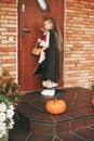 Little girl in a fairy costume with a basket in her hands is knocking on the door during the Halloween celebration Royalty Free Stock Photo