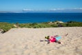 Little girl falling on sand with Tarifa and Africa on the horizon