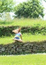 Little girl falling on stone wall