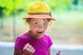 A little girl in a fashion hat hugged her mouth in chocolate. Portrait of a cunning child