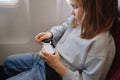 a little girl fastens her seat belt in a seat on board the plane.