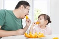 Little girl with father eating orange