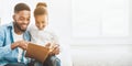 Little girl and father enjoying reading book together