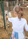 Little girl feeding goat.