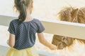 Little girl feeding horse in her farm through a white wooden fen Royalty Free Stock Photo