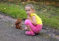 Little girl feeding squirrel with nuts