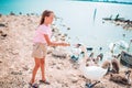 Little girl sitting on the beach with swans Royalty Free Stock Photo