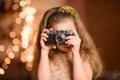little girl in a festive dress with flowing hair takes pictures on a vintage camera Royalty Free Stock Photo