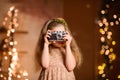 little girl in a festive dress with flowing hair takes pictures on a vintage camera Royalty Free Stock Photo