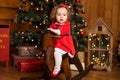 Little girl in a festive red dress on a wooden swing rocking horse. Christmas parties are a fabulous time for children