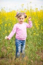 A little girl in a field of rapeseed with a bunch of chamomiles