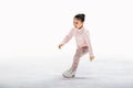 Little girl figure skater in light pink tracksuit with smile skates on the ice on an indoor skating rink Royalty Free Stock Photo