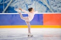Little girl figure skater in light pink tracksuit with smile skates on the ice on an indoor skating rink Royalty Free Stock Photo
