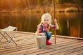 Little girl fisherman with a fishing rod and a bucket of fish on a wooden pier Royalty Free Stock Photo