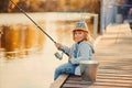 A little girl fishing with a fishing rod from a pontoon or pier on the pond fish farm Royalty Free Stock Photo