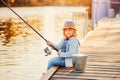 A little girl fishing with a fishing rod from a pontoon or pier on the pond fish farm Royalty Free Stock Photo