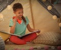 Little girl with flashlight reading book in tent Royalty Free Stock Photo